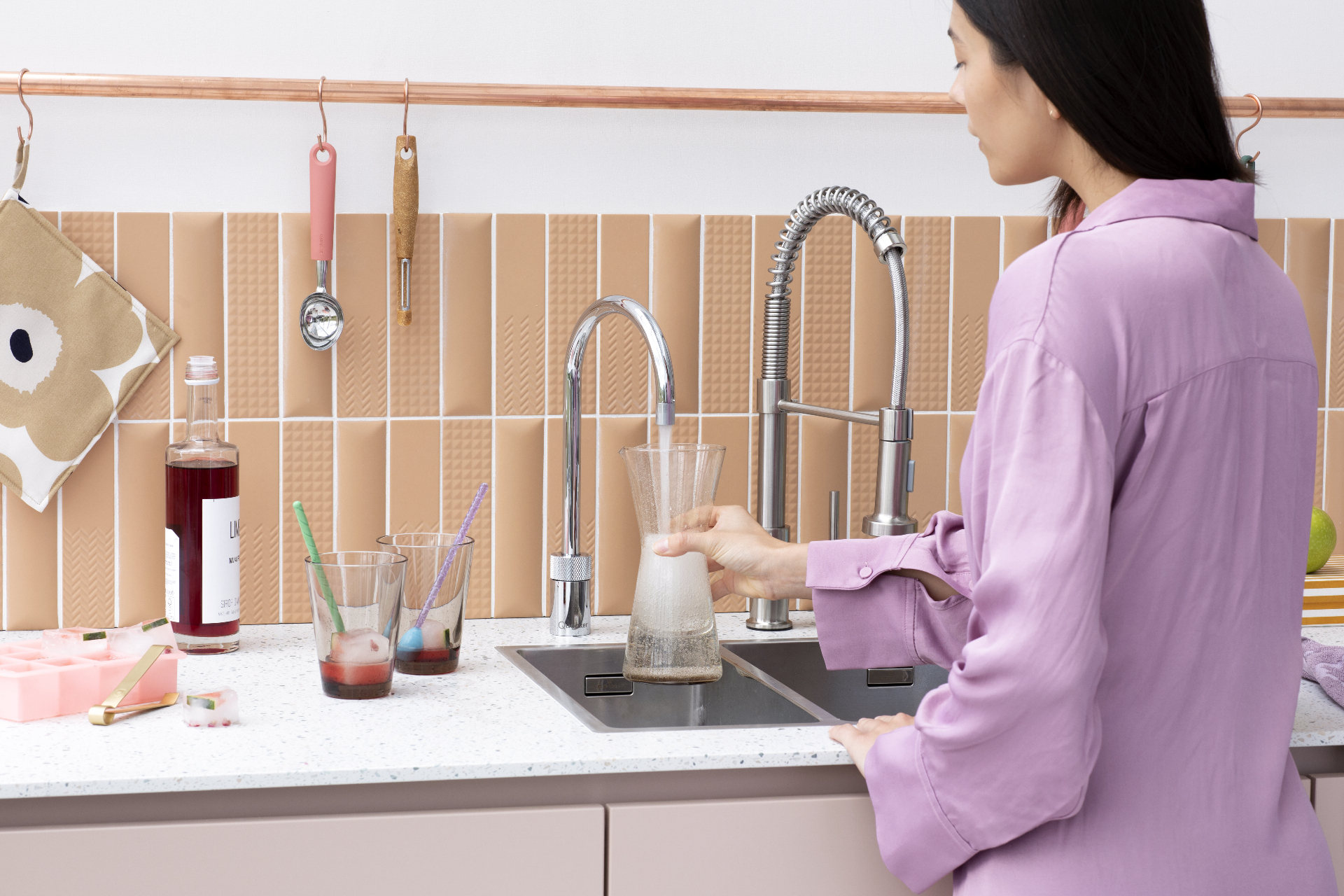 Woman filling a coffee carafe with boiling water at a Nordic Round single tap in chrome
