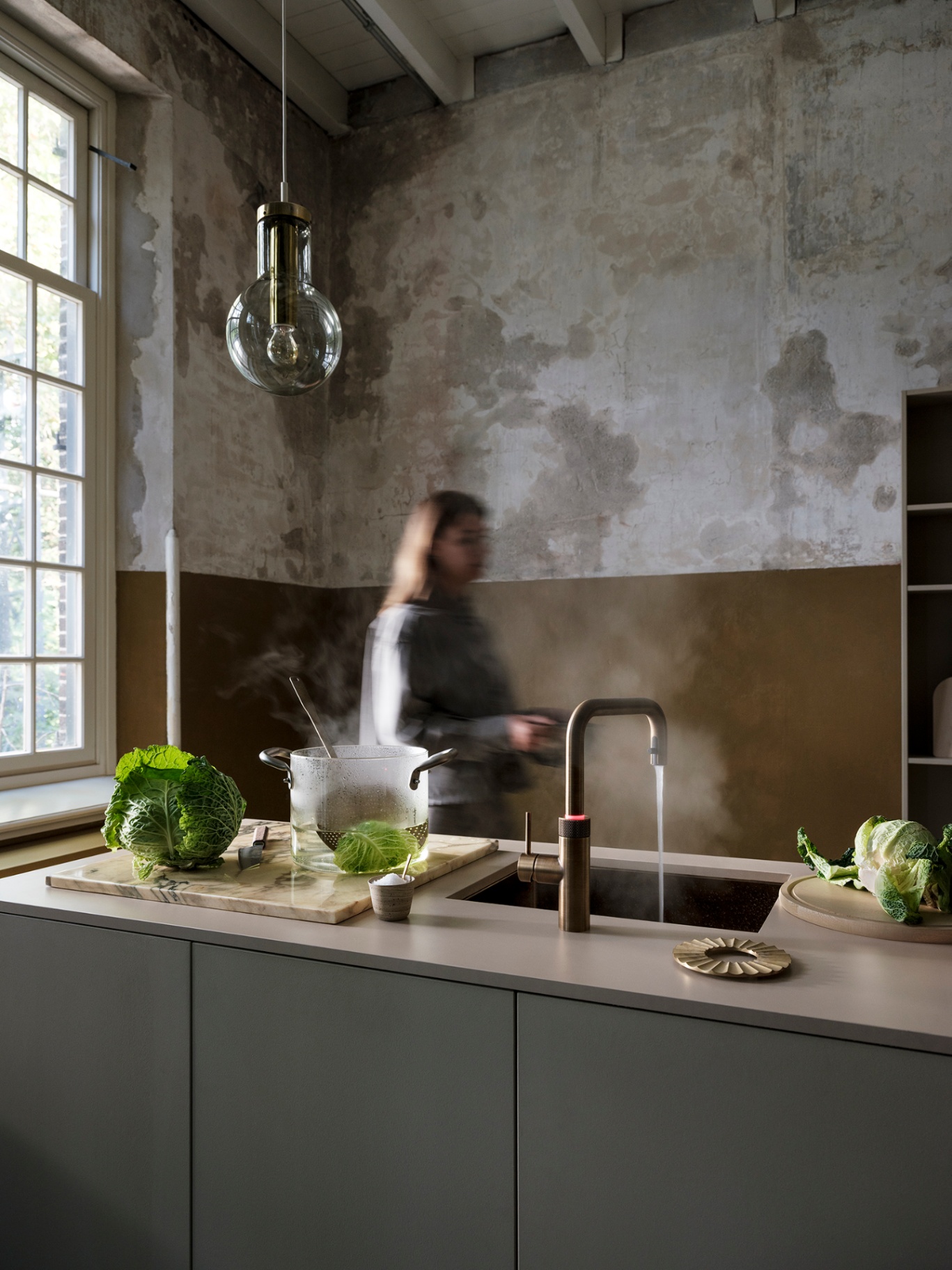 Flex Square patinated brass Quooker filling a pot with boiling water over savoy cabbage in a moody loft