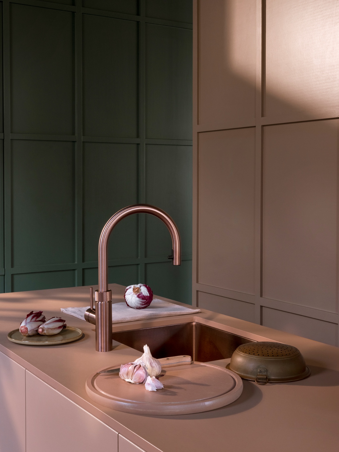 Flex Round rose copper Quooker beside copper sink with garlic and radicchio on a blush worktop
