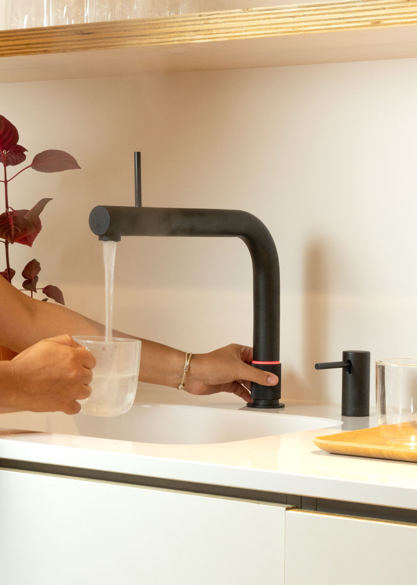Quooker Front in matte black boiling water tap — pouring 100 °C boiling water, pouring water, closeup in a real customer kitchen. Genuine Quooker product supplied by Watertap.eu.