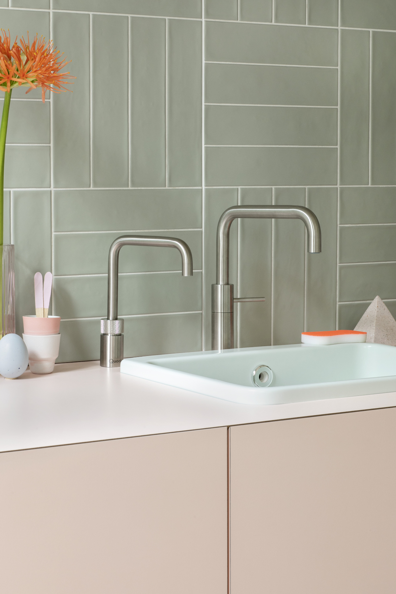 Nordic Twin square taps in stainless steel against sage green tiled backsplash