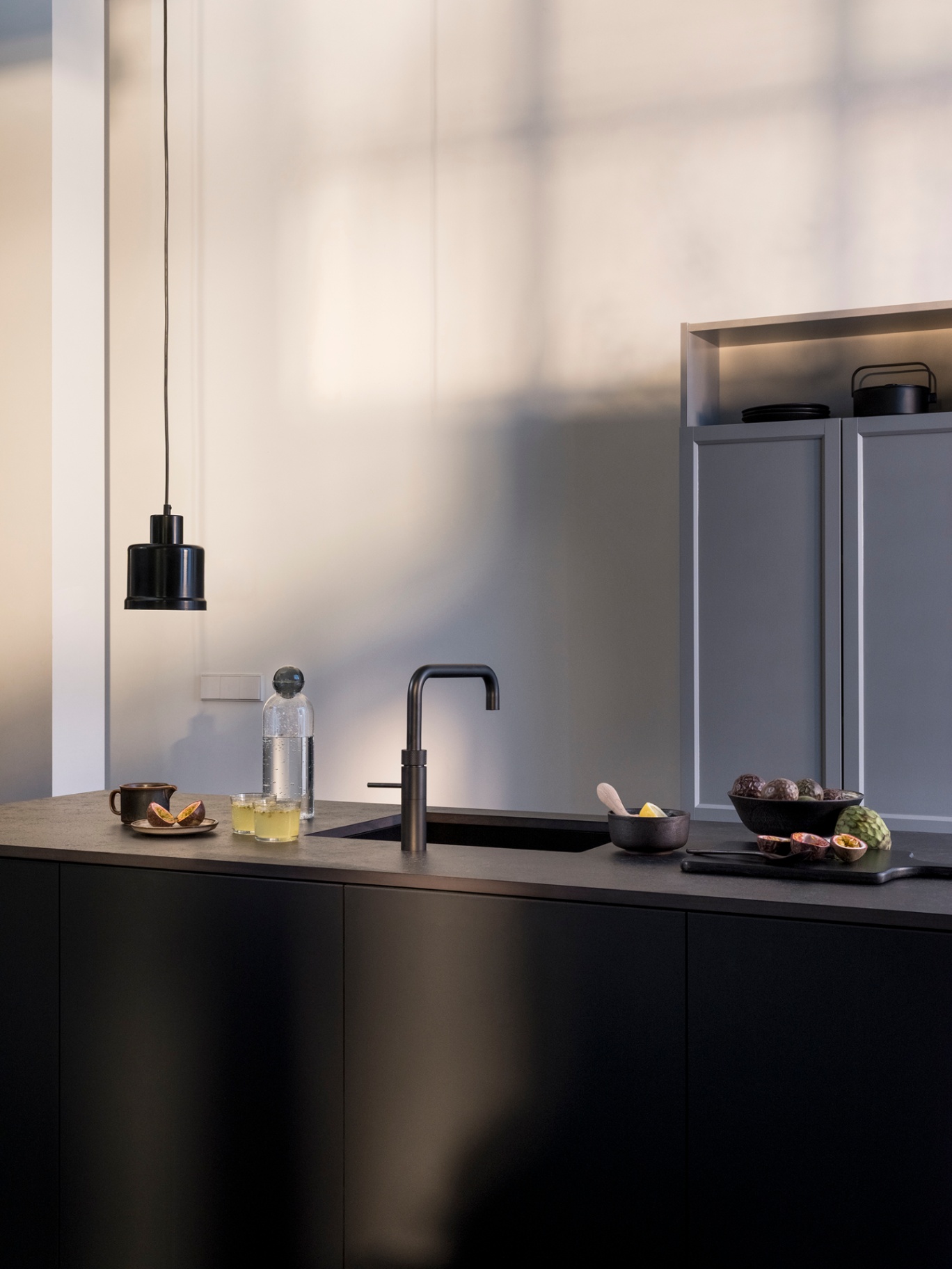 Editorial countertop composition with a black Fusion Square Quooker and sparkling water setup