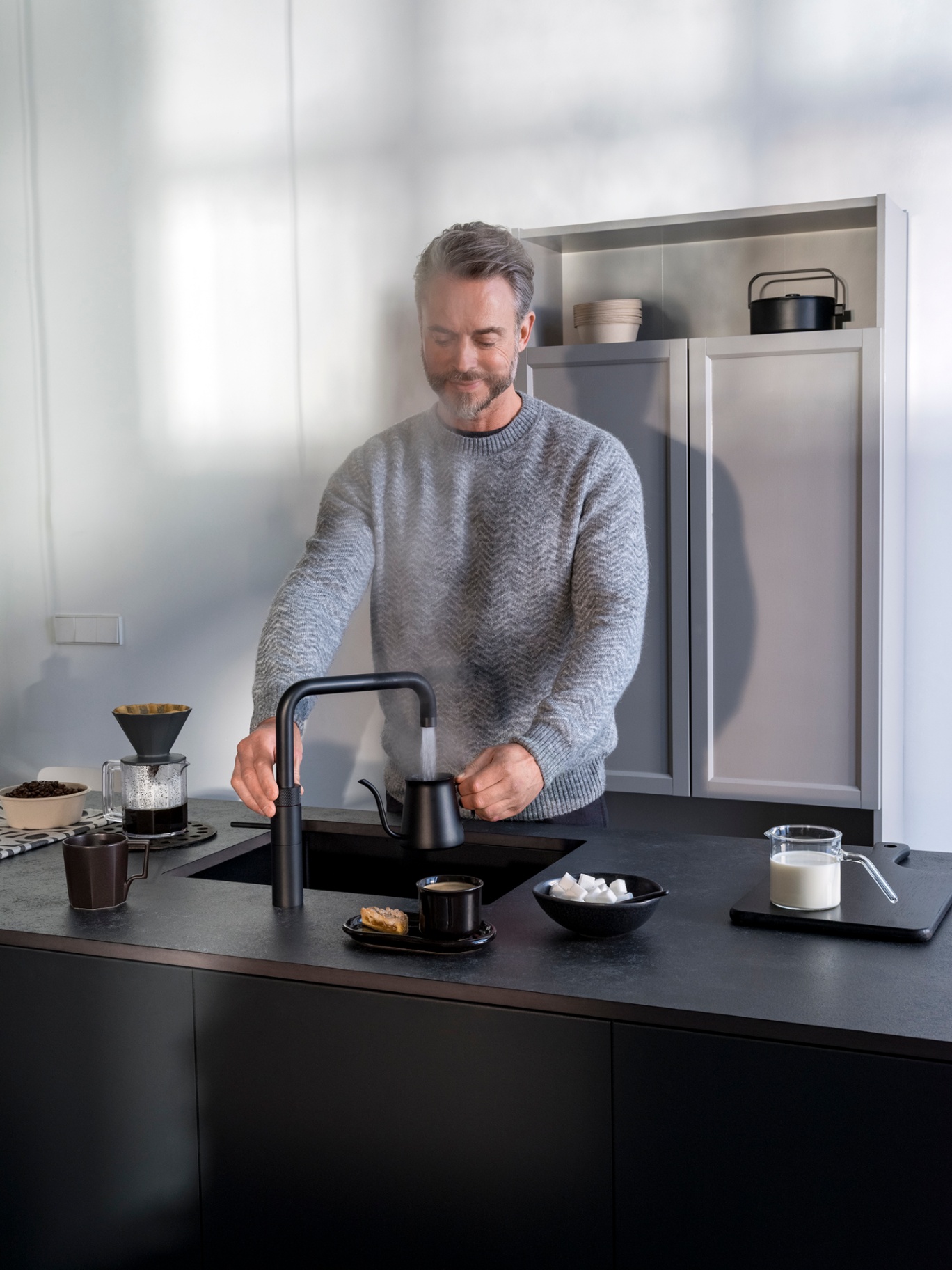 Close-up of a black Fusion Square Quooker pouring boiling water into a coffee kettle