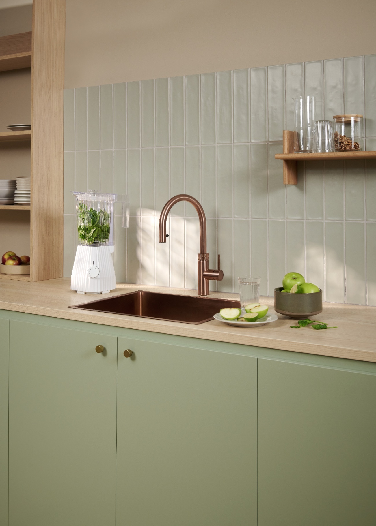 Flex Round rose copper Quooker beside a green smoothie blender in a sage tile kitchen