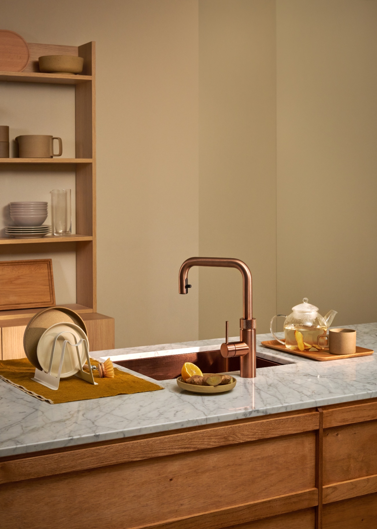 Still life of Flex Square rose copper Quooker with glass teapot and ginger on Carrara marble