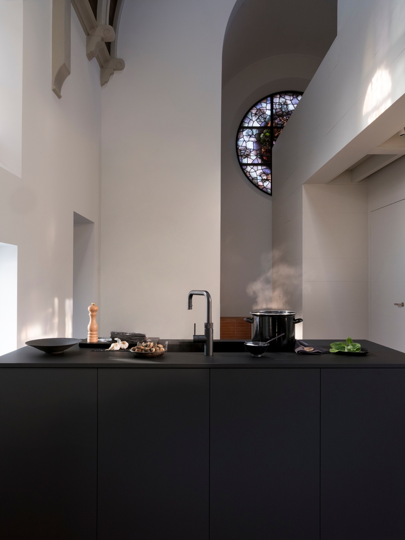 Still life of a Flex Square black Quooker with steaming stockpot in a monumental chapel kitchen