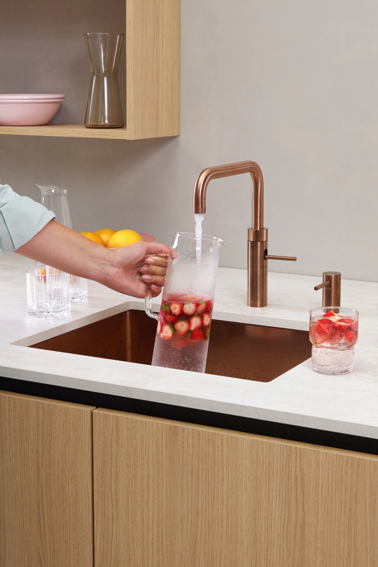 Rose copper Fusion Square Quooker filling a carafe with strawberry sparkling water
