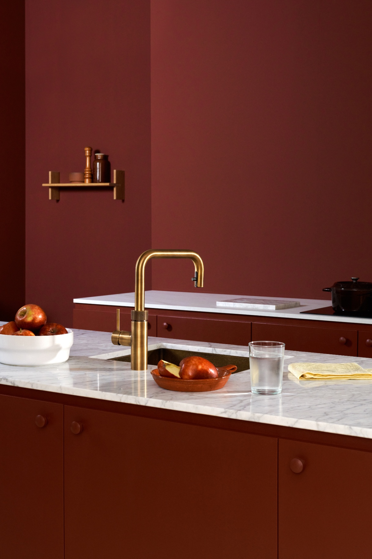 Flex Square patinated brass Quooker on Carrara marble in a deep-red kitchen with pears and apples