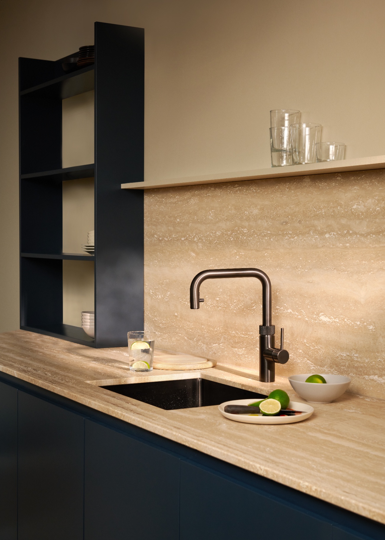 Editorial still life of a Flex Square gun metal Quooker with lime water on a travertine worktop