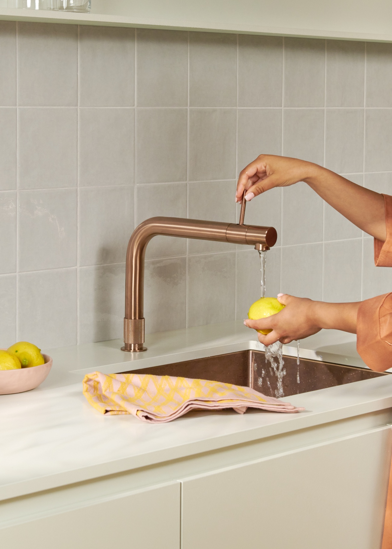 Quooker Front in rose copper — rinsing a lemon in a pastel kitchen, available at Watertap.eu