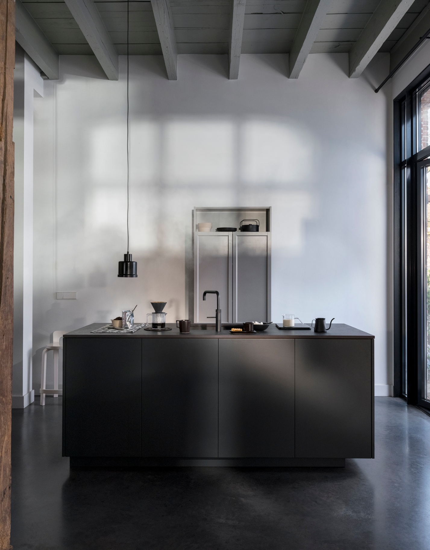Architectural still life of a black Fusion Square Quooker with brewing ritual on a dark island