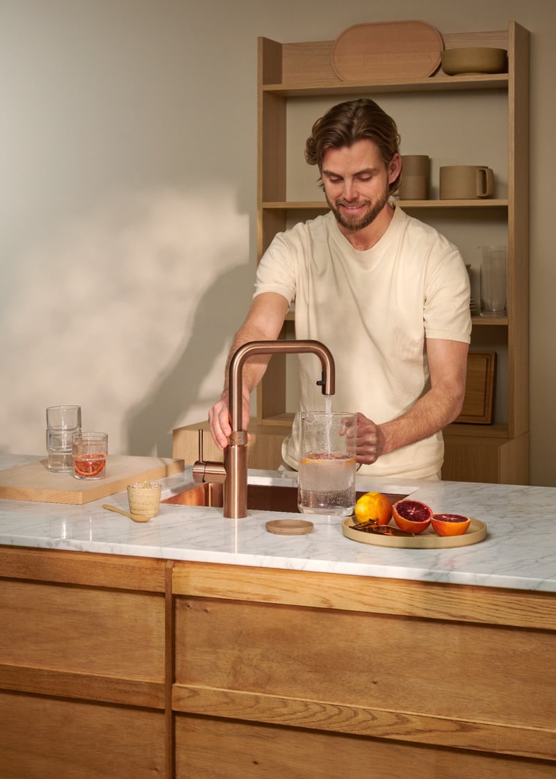 Quooker Flex Square in rose copper boiling water tap — with blood orange in a real customer kitchen. Genuine Quooker product supplied by Watertap.eu.