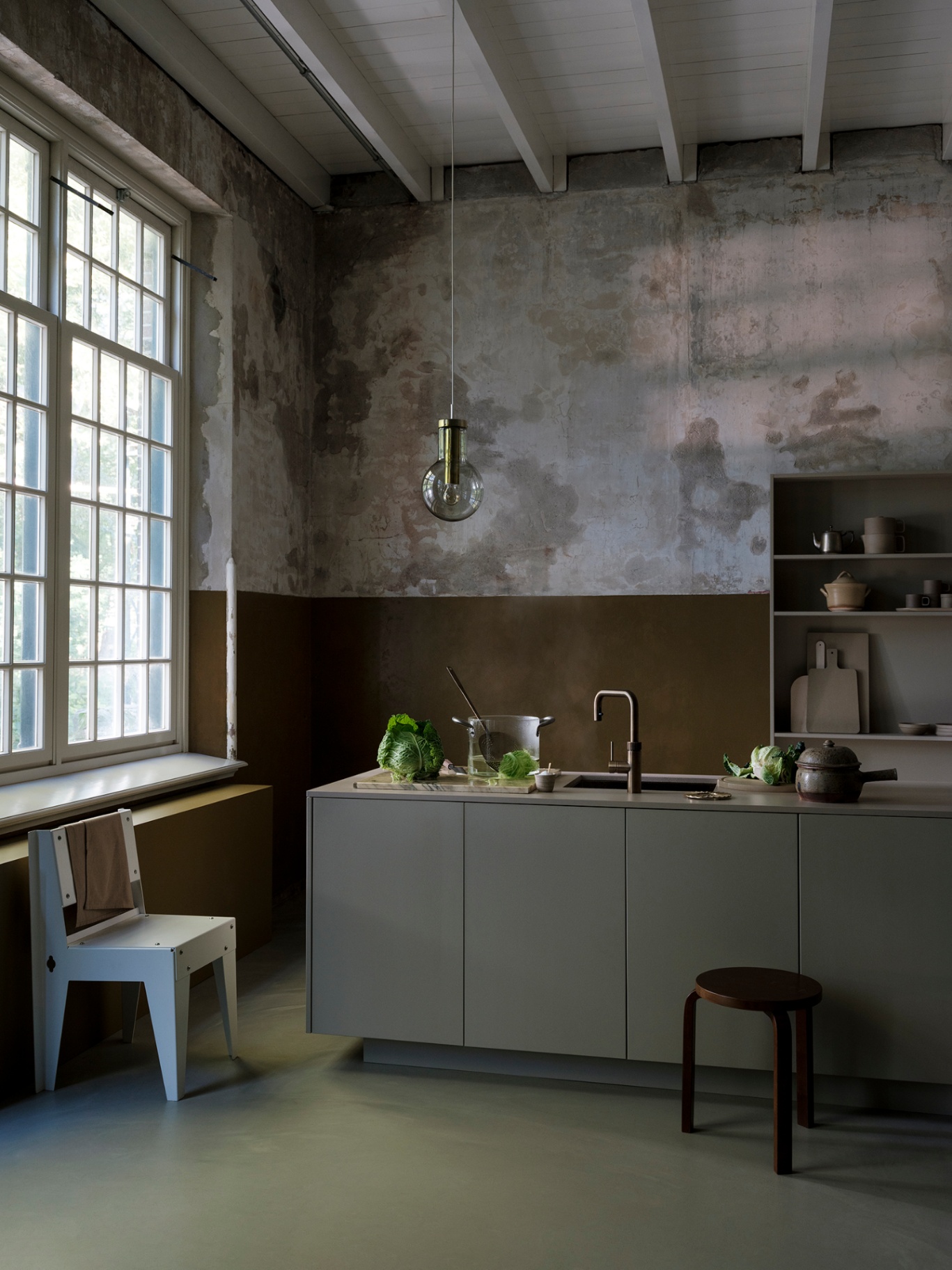 Architectural loft kitchen featuring a Flex Square patinated brass Quooker under weathered plaster walls