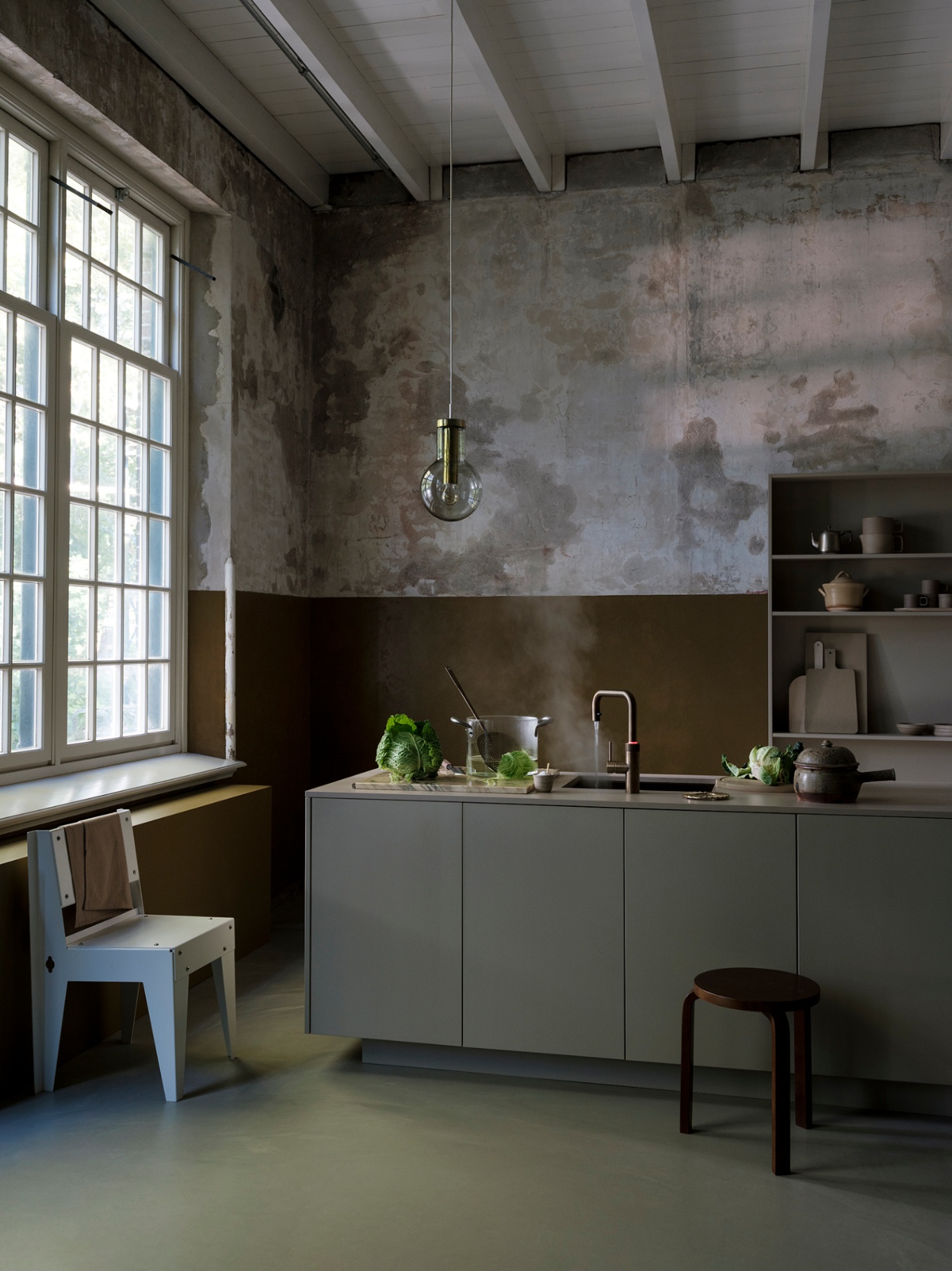 Wide editorial view of a Flex Square patinated brass Quooker steaming above a pot in a monumental loft