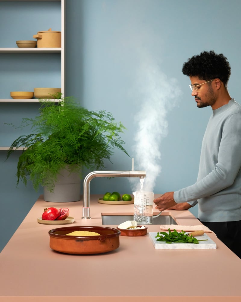 Quooker Front in stainless steel boiling water tap — pouring 100 °C boiling water, cooking couscous in a real customer kitchen. Genuine Quooker product supplied by Watertap.eu.