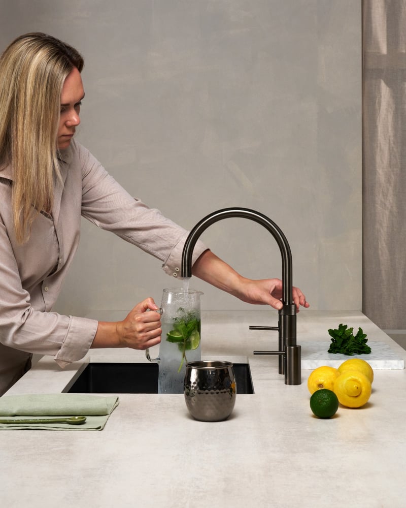 Quooker Fusion Round in gunmetal boiling water tap — mixing a virgin mojito in a real customer kitchen. Genuine Quooker product supplied by Watertap.eu.