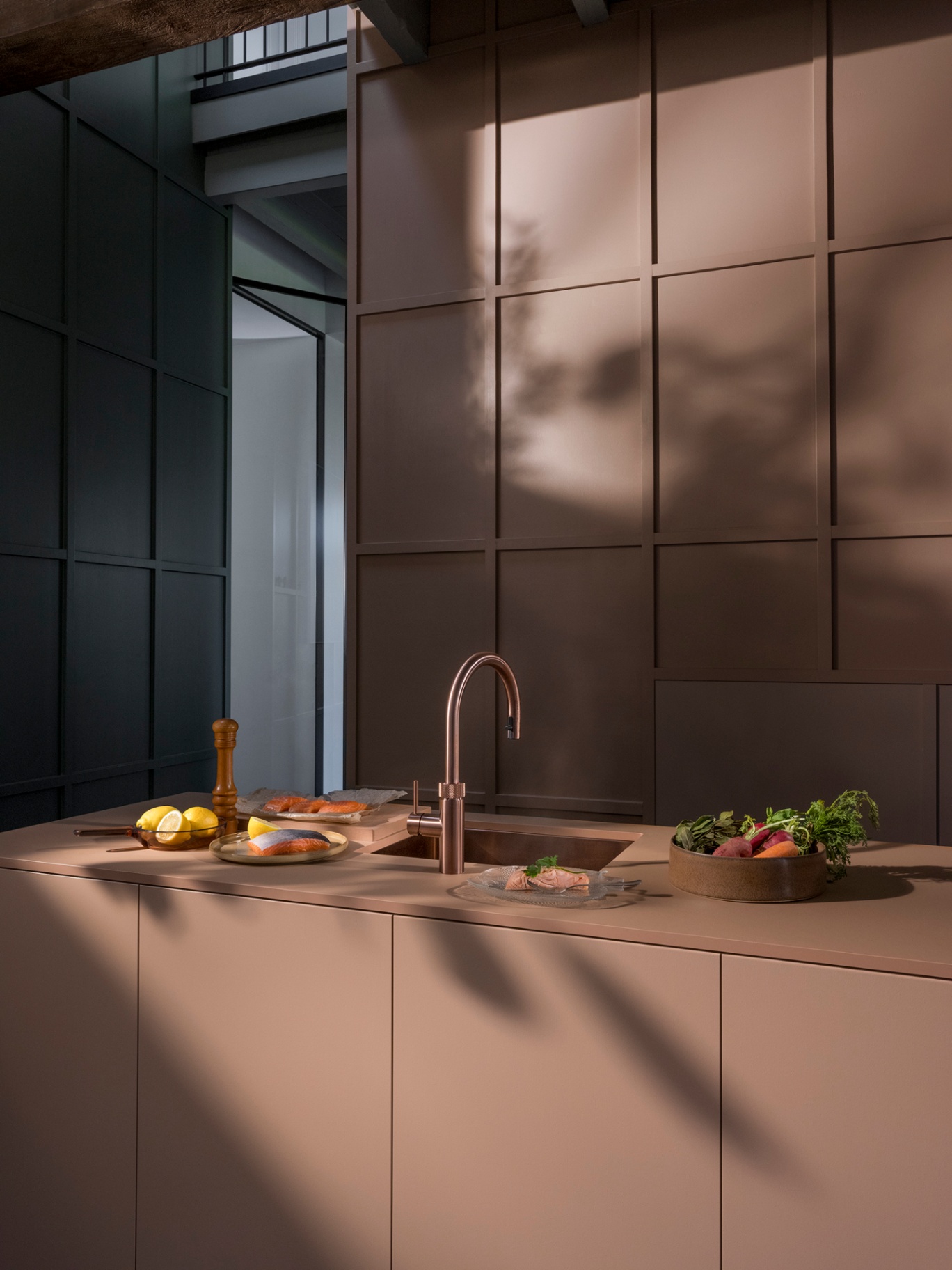 Still life of a Flex Round rose copper Quooker in a panelled blush kitchen with salmon and lemons