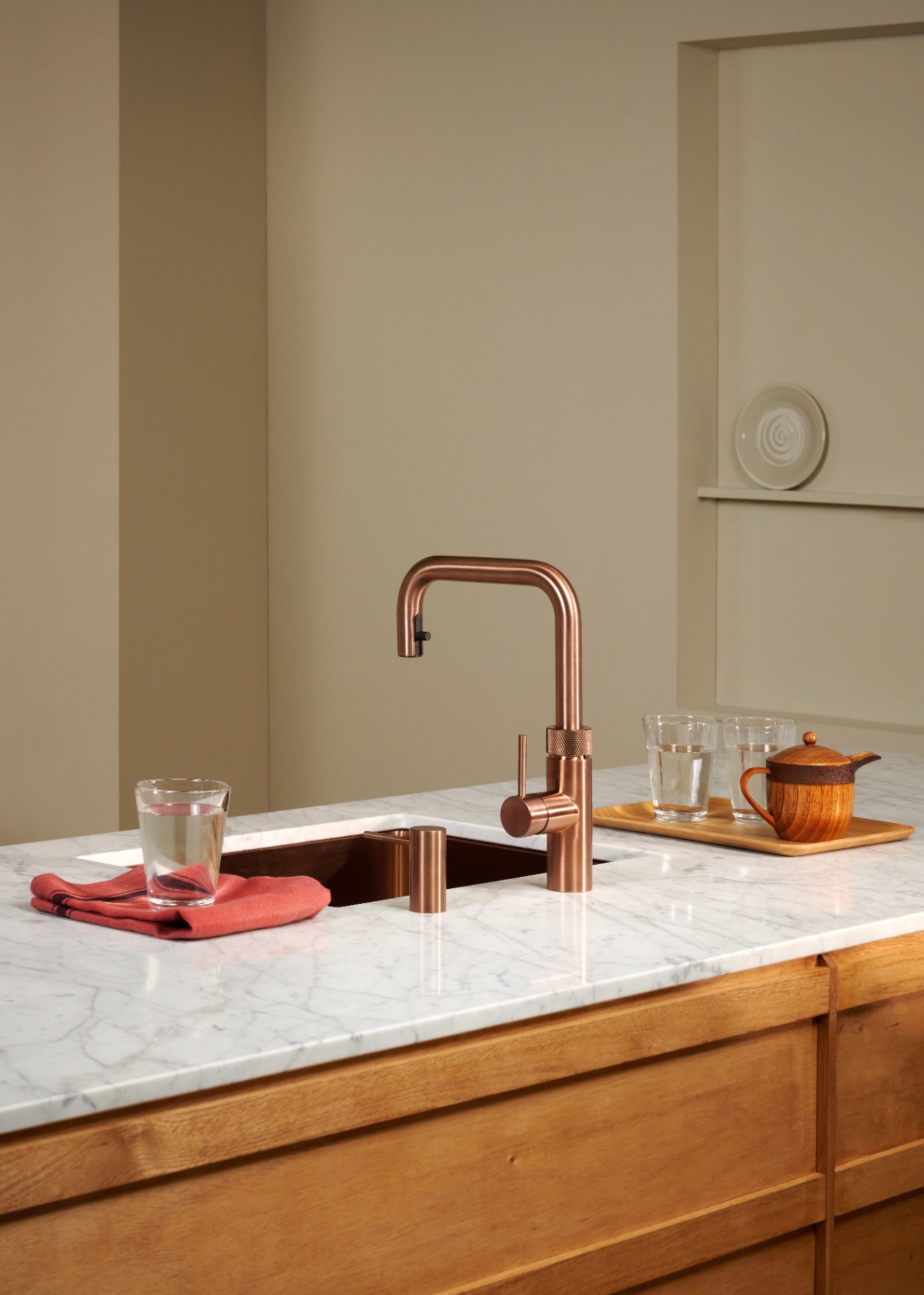 Editorial still life of a Flex Square rose copper Quooker with chilled water glasses on Carrara marble