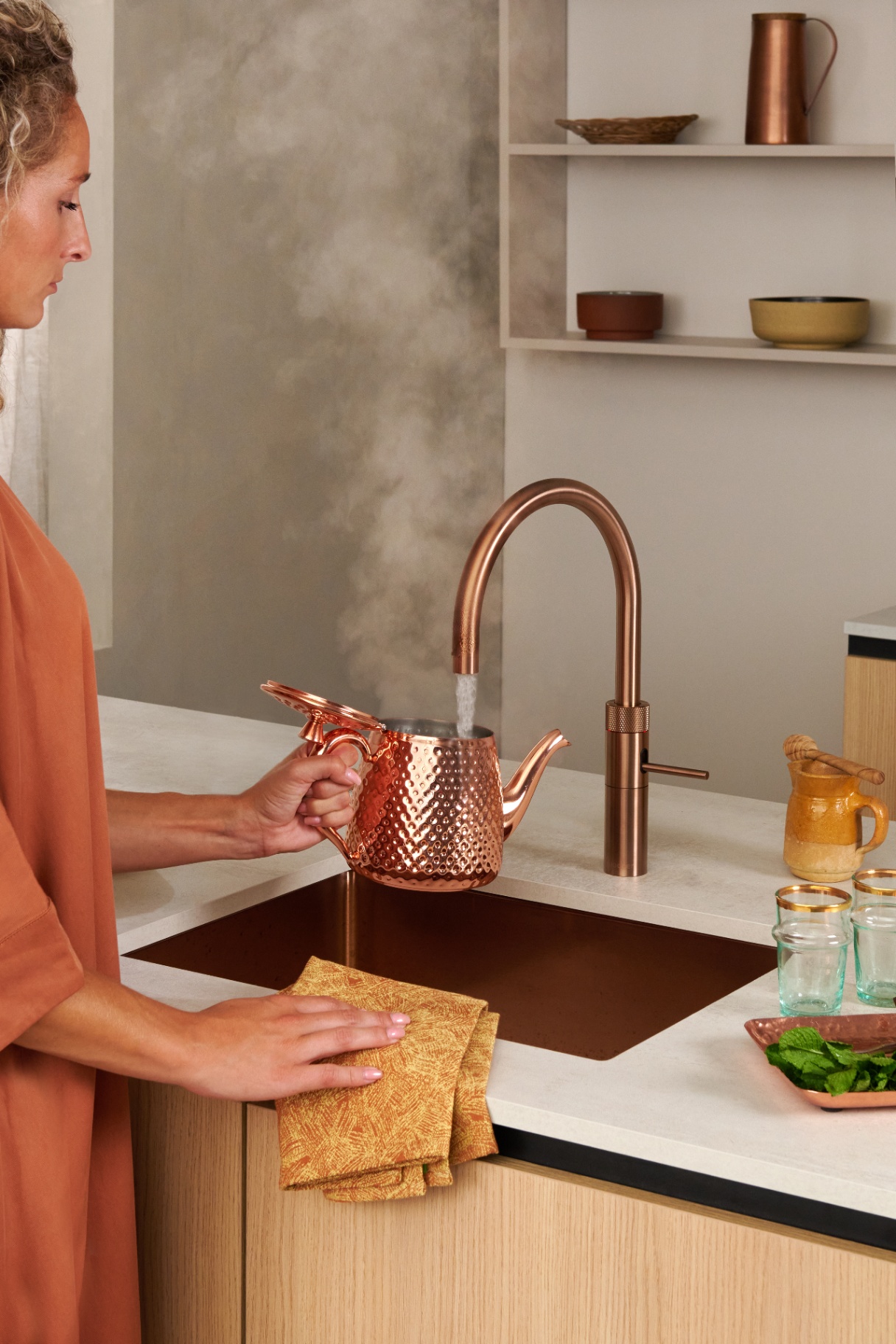 Quooker Fusion Round in rose copper filling a hammered copper Moroccan teapot
