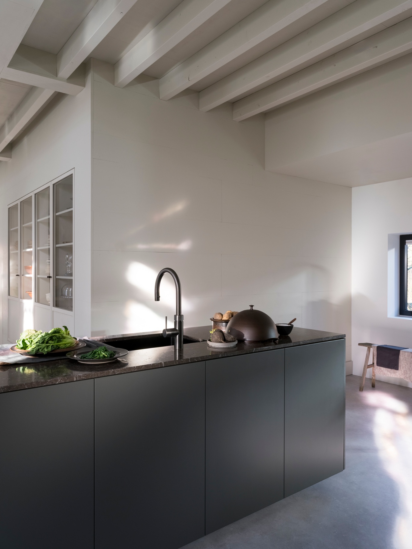 Editorial still of a Flex Round gun metal Quooker on a dark marble island with copper pans and greens