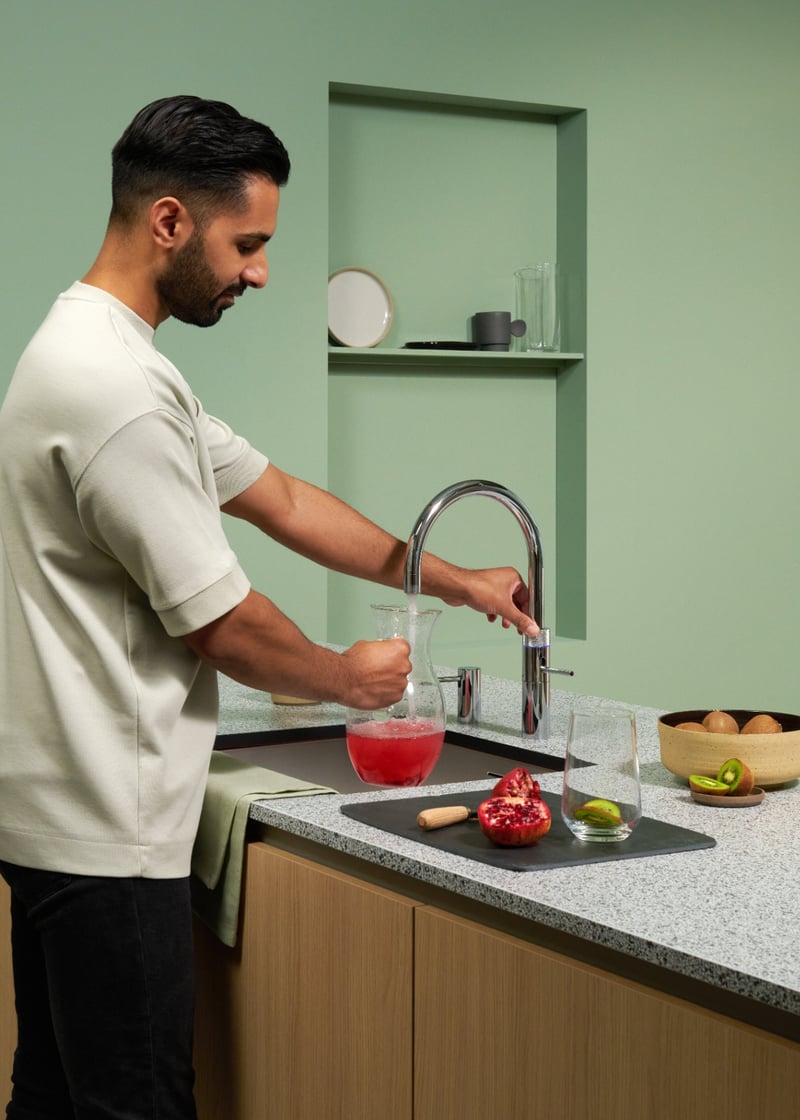 Quooker Fusion Round in chrome boiling water tap — with kiwi garnish in a real customer kitchen. Genuine Quooker product supplied by Watertap.eu.