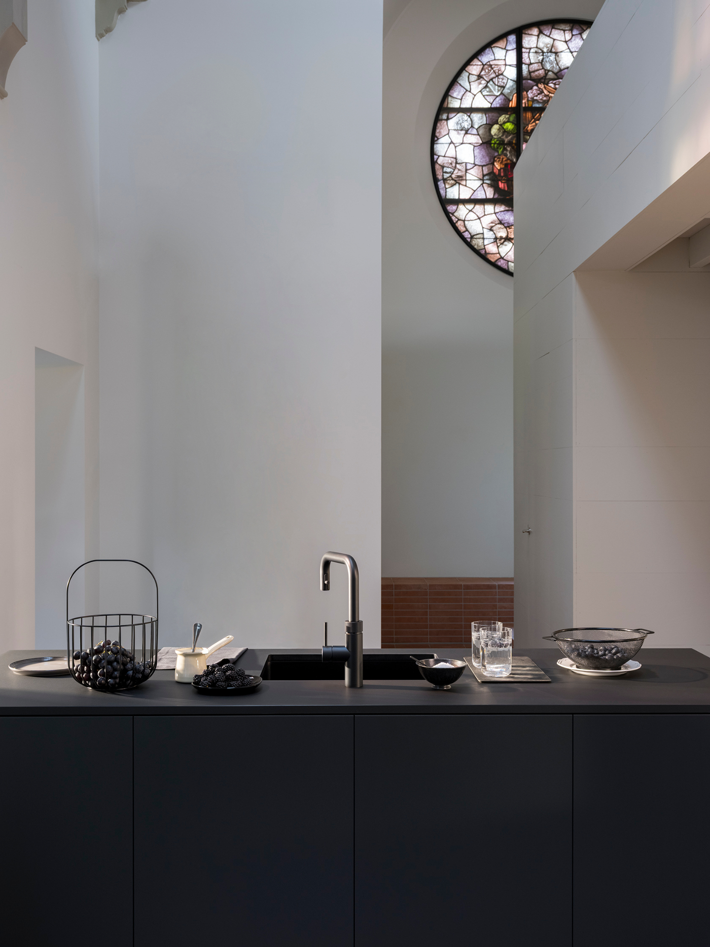 Editorial still of a Flex Square black Quooker with grapes, blackberries and blueberries on a matte black worktop