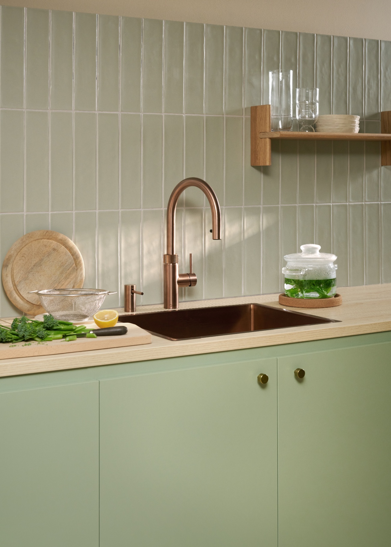 Flex Round rose copper Quooker with blanched broccoli in a glass pot on a soft green tile kitchen